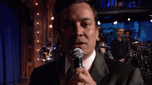 a man in a suit and tie is holding a microphone in front of his face