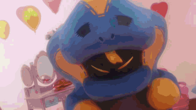 a blue and yellow stuffed animal is sitting in front of a vanity with balloons in the background