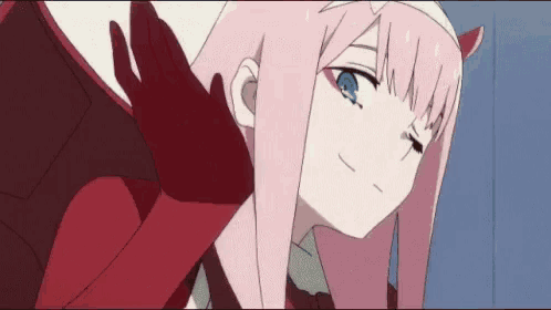 a girl with pink hair and blue eyes is wearing red gloves .