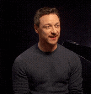 a man wearing a black sweater is smiling and looking at the camera