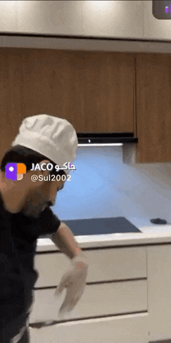 a man wearing a chef 's hat and gloves is standing in a kitchen .