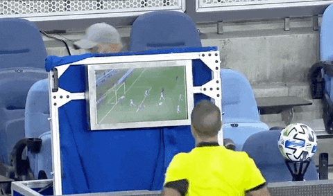 a referee is watching a soccer game on a monitor