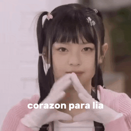 a young girl making a heart shape with her hands and the words corazon para lia written below her