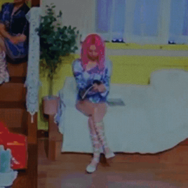 a woman with pink hair sits on a couch