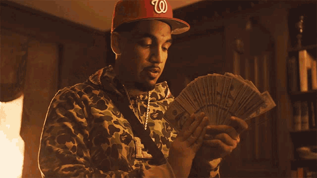a man wearing a hat with the letter w on it is holding a bunch of money