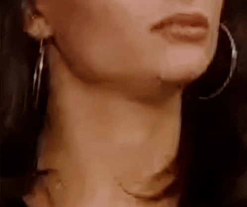 a close up of a woman 's neck with a necklace and hoop earrings .