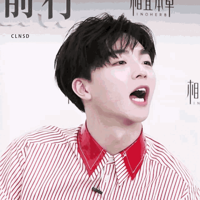 a young man wearing a red and white striped shirt has his mouth open in front of a sign that says linherb