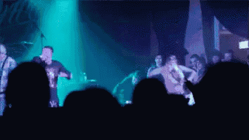 a man singing into a microphone in front of a crowd that is watching
