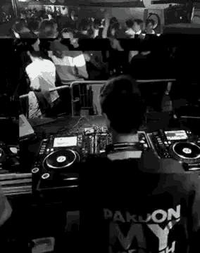 a dj is sitting at a table in front of a crowd at a party .