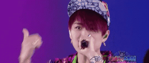 a young man wearing a hat is singing into a microphone .