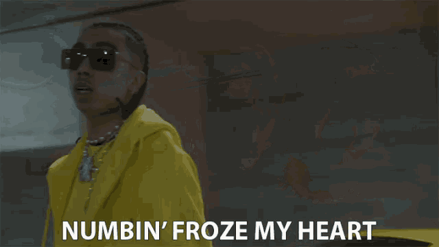 a man wearing sunglasses and a yellow jacket says numbin ' froze my heart