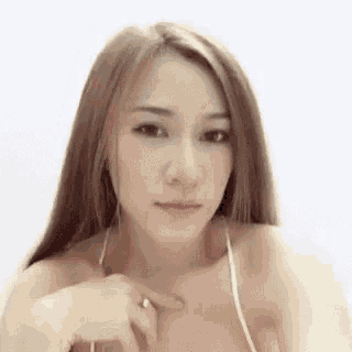 a woman in a bikini is looking at the camera while holding her breast .
