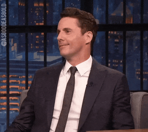 a man in a suit and tie is sitting in front of a microphone ..