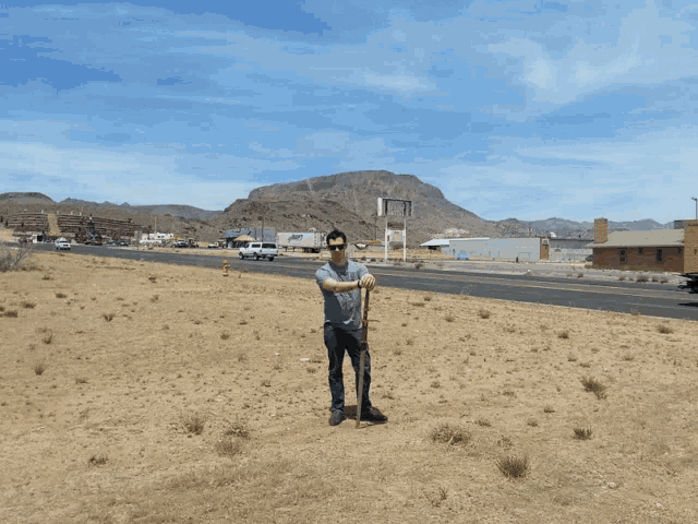 a man holding a sword in front of a road with mountains in the background