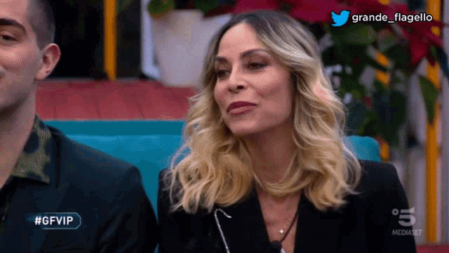 a woman in a black jacket sits next to a man in a black shirt on a television screen that says #gfvip on it