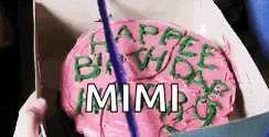 a person is holding a birthday cake in a box that says `` happy birthday mimi '' .