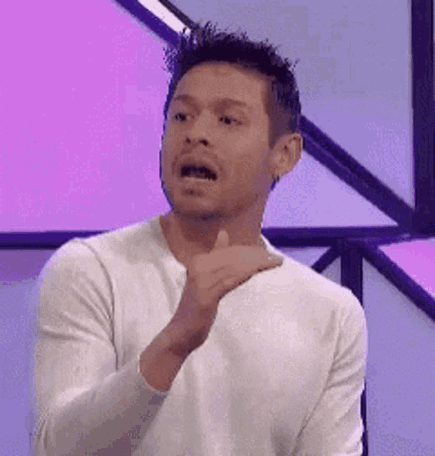 a man in a white shirt is making a funny face while giving a thumbs up sign .