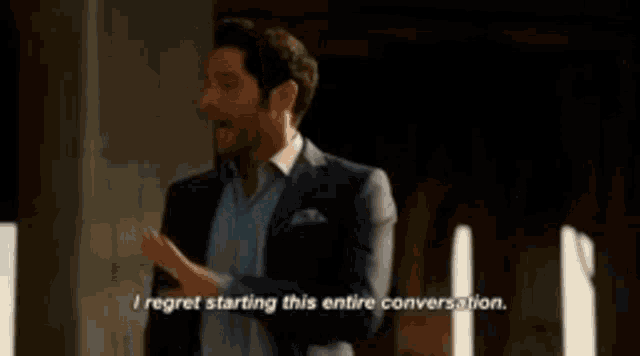 a man in a suit is talking to another man in a blue shirt .