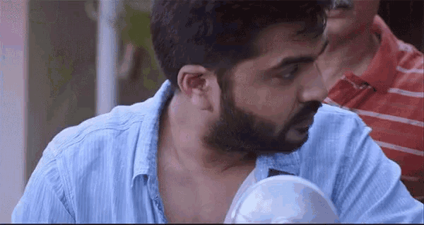 a man with a beard is wearing a blue shirt and a red striped shirt