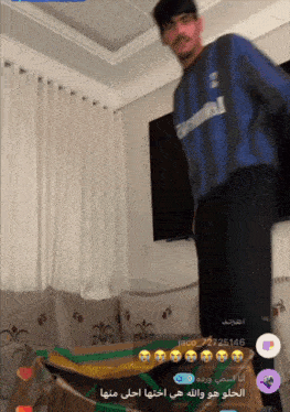 a man in a blue shirt with the number 1 on it is standing in a living room