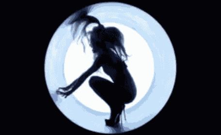 a silhouette of a woman kneeling in a circle with her hair blowing in the wind .