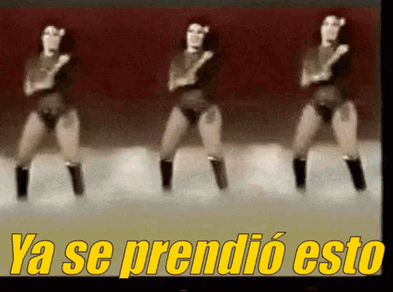 three women are dancing in front of a sign that says ya se prendido esto