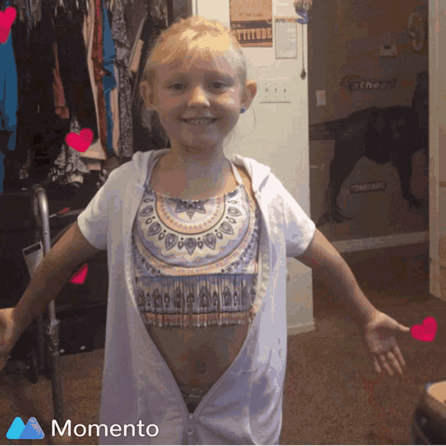 a little girl wearing a bikini top and a white shirt with the word momento on the bottom right