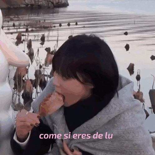 a woman is eating a piece of food with the words come si eres de lu written below her