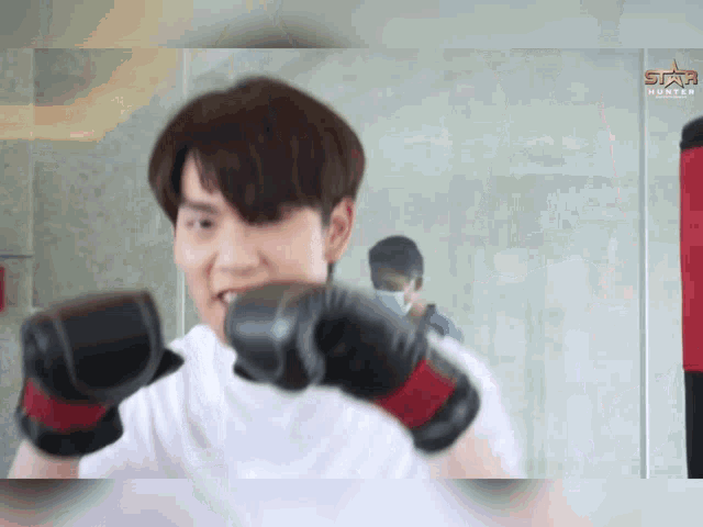 a man is wearing boxing gloves in front of a punching bag .