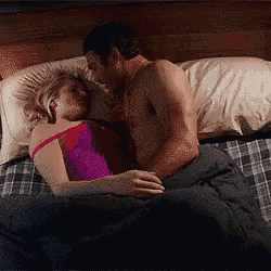 a man and a woman are kissing while laying on a bed