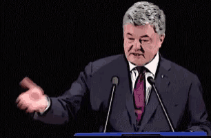 a man in a suit and tie stands at a podium giving a speech