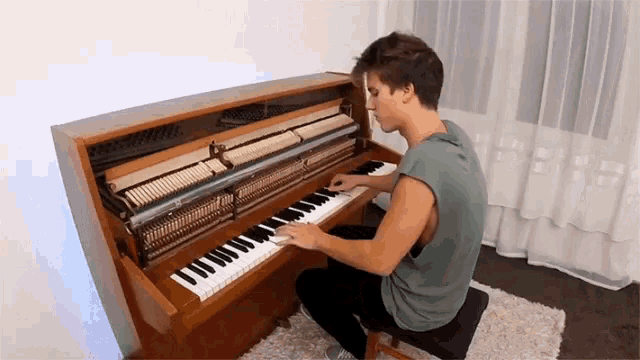 a man is playing a piano with the lid open