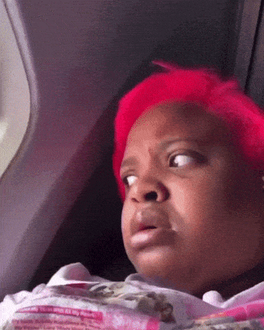 a little girl with red hair is looking out of a window