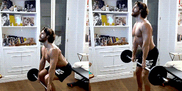 a shirtless man is squatting down with a barbell in a living room