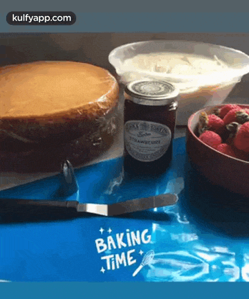 a jar of strawberry jam sits next to a cake