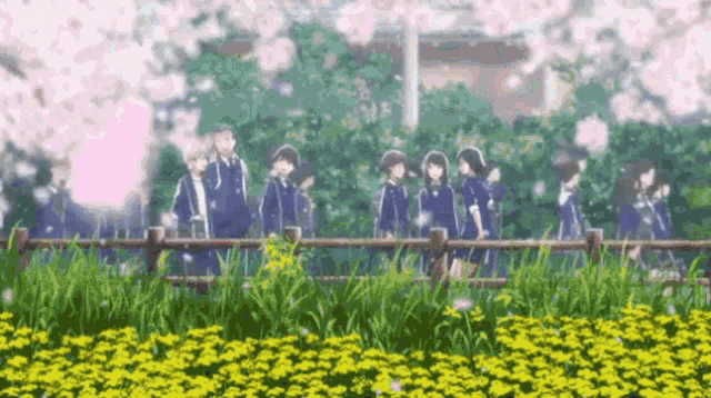 a group of students are walking across a fence in a field of flowers .