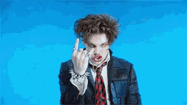 a man in a suit and tie is making a funny face while standing in front of a blue background .