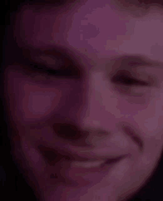 a close up of a man 's face with purple eyes and a smile .