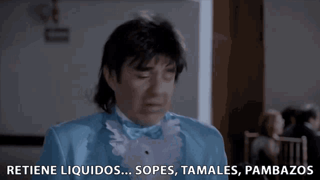 a man in a blue tuxedo is saying " retiene liquidos "