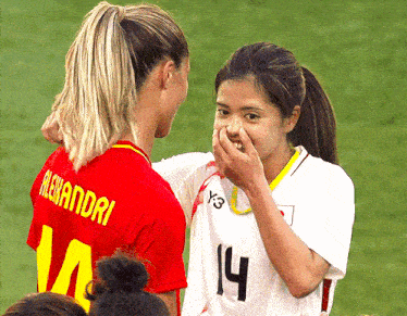 two female soccer players one with the number 14 on her shirt