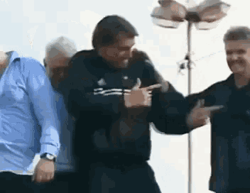 a group of men are standing next to each other and dancing .