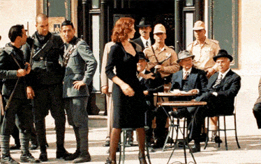a woman in a black dress is standing in front of a group of men in military uniforms