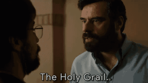 a man with a beard and glasses is talking to another man with the words the holy grail below him