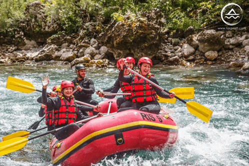 a group of people are rowing a red raft with the number 9 on it