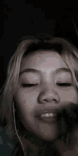 a close up of a woman 's face with her eyes closed and headphones on .