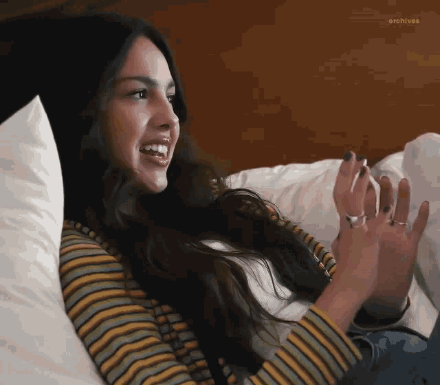 a woman in a striped shirt is laying on a bed .