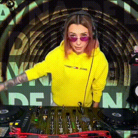 a woman in a yellow tommy jeans hoodie is playing a dj set