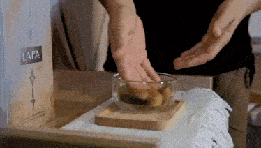 a person 's hand is reaching into a bowl of food on a table next to a box that says lafa