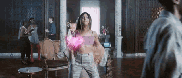 a woman in a pink top and plaid pants is standing in a room