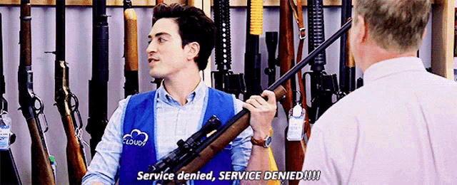 a man in a blue vest with the word cloud on it is holding a rifle